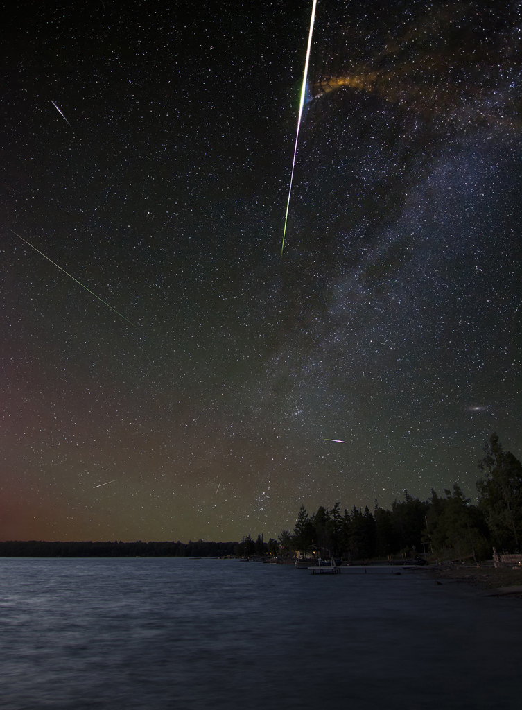 2023-0007-Astroscape Perseid meteors capturing the explosive residue of a massive fireball. The image also shows green and red airglow, the Andromeda galaxy rising above the treeline and our Milky Way with associated dust lanes. - Shakeel Anwar